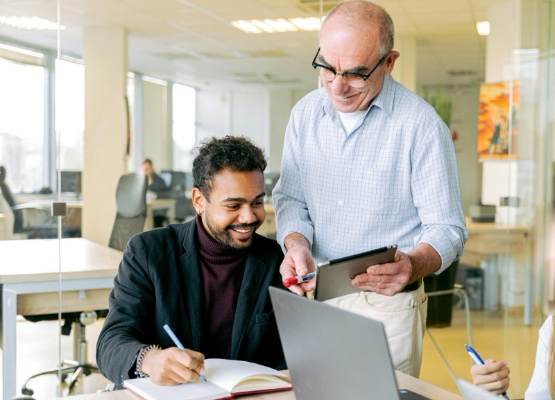 Senior trainer coaching a colleague at a desk